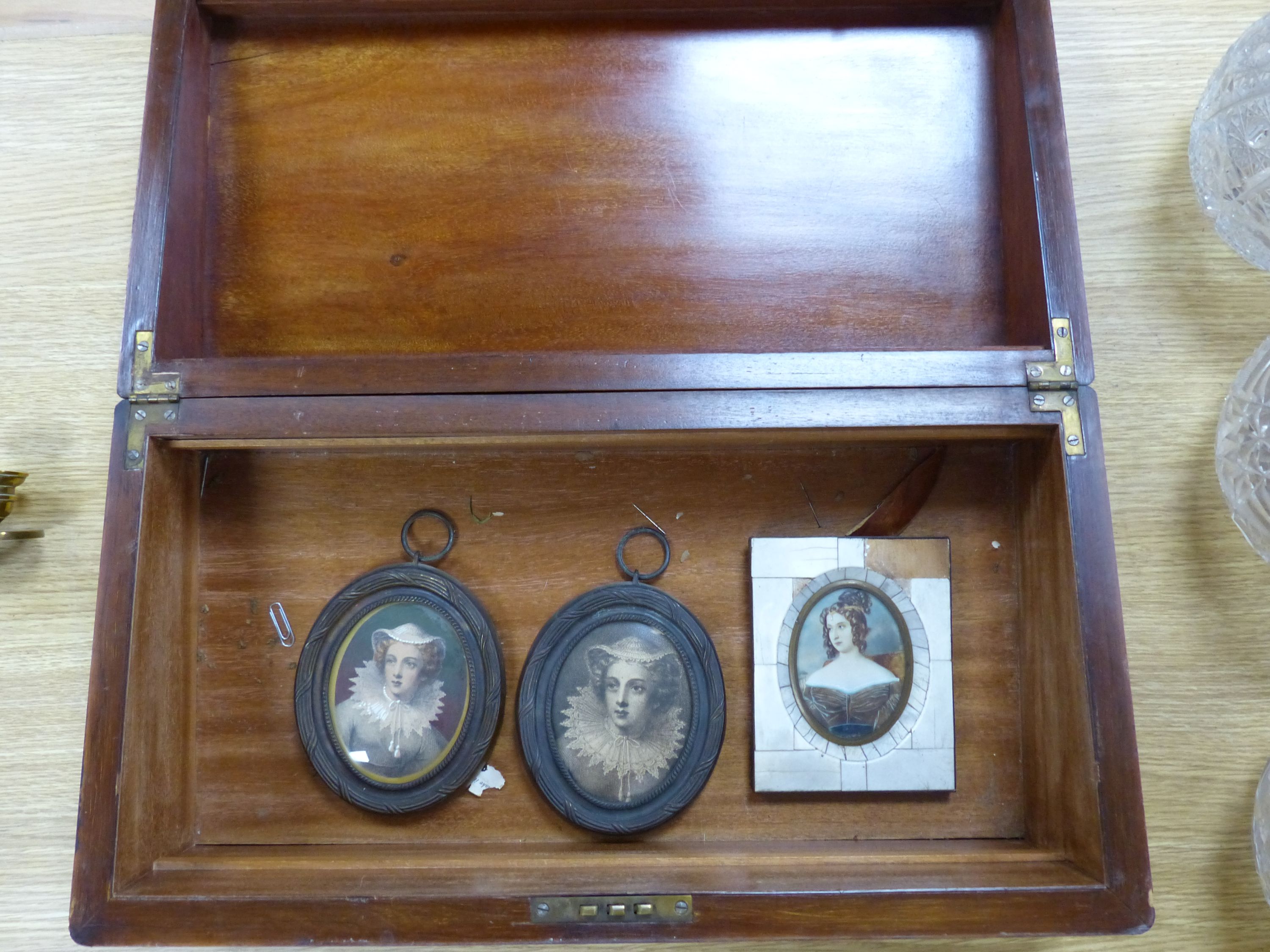 Two brass framed portraits and a portrait miniature and a mahogany writing slope, width 50cm